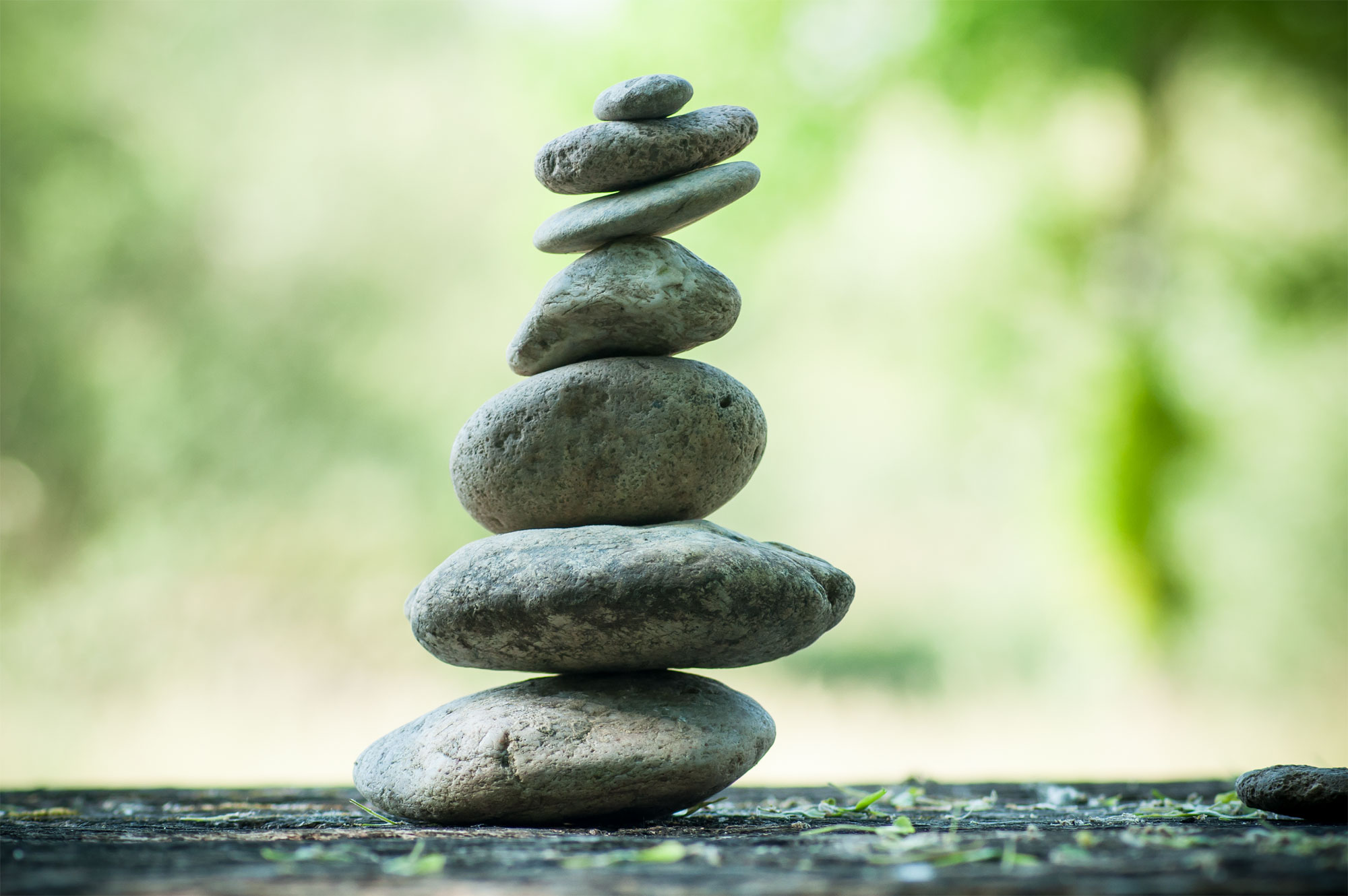 closeup of stones balance on wooden table on green blurred background