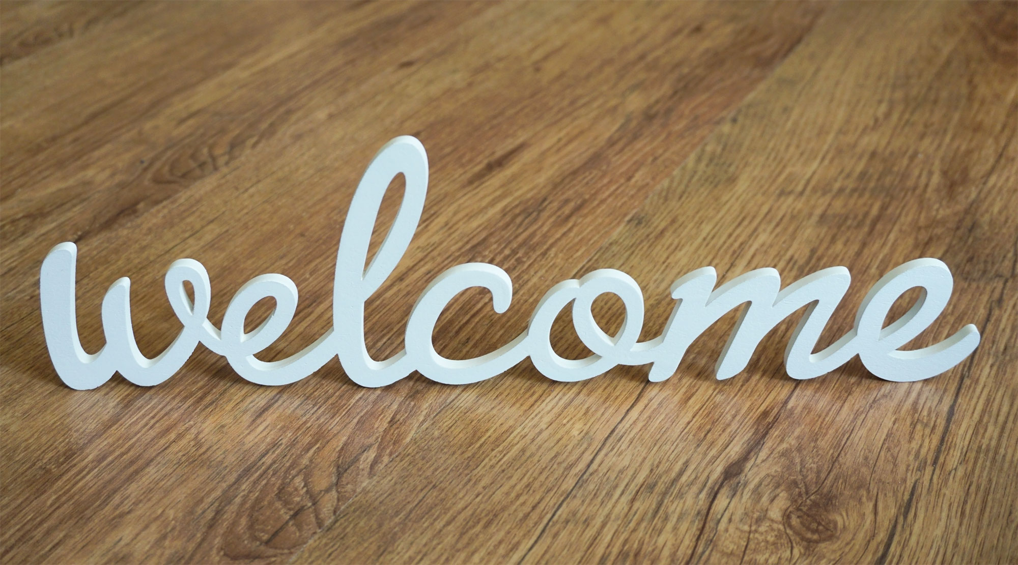 Schriftzug "welcome" auf holzigem Untergrund